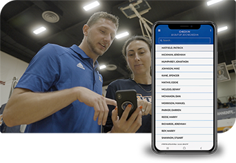 Photo of a coach talking to a female athlete while both are looking at a phone. A mobile device with a screenshot from the Ryzer Go app sits beside it.